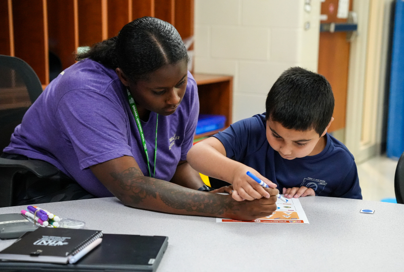 paraprofessional helps a student practice writing